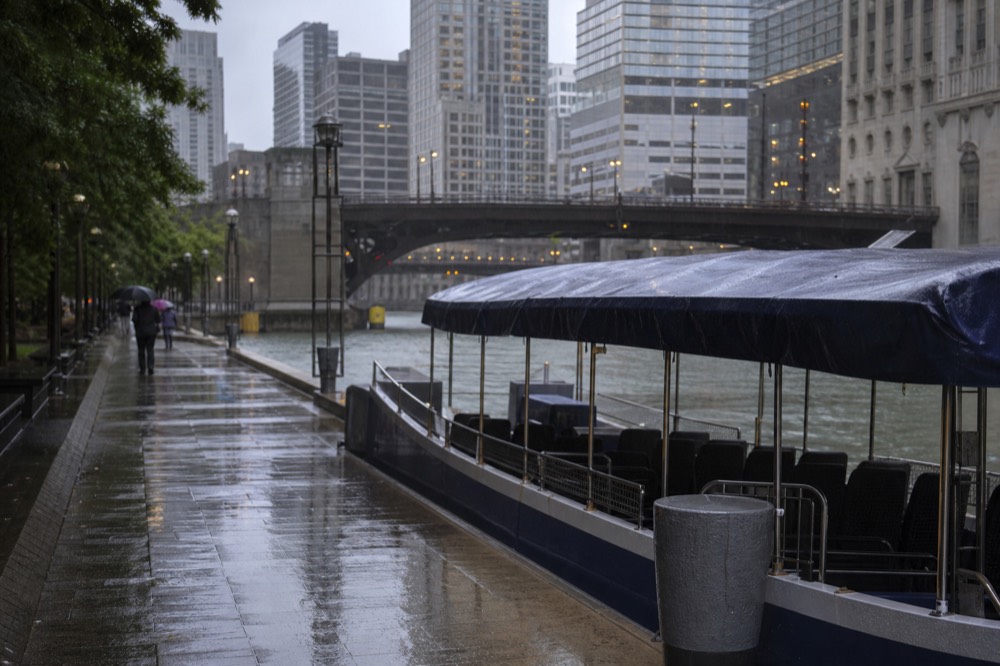 Raindrops on the canopy of a river cruise boat with the Chicago skyline blurred in the background, no text, no logos, no people.
