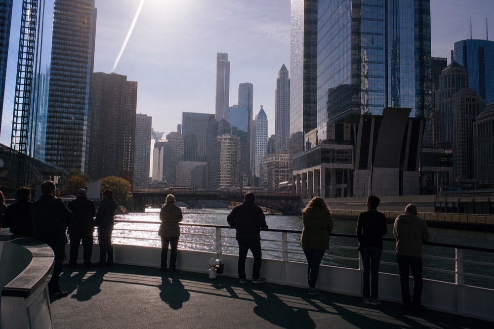 Children leaning on a boat railing watching the Chicago Riverwalk pass by from a cruise, no text, no logos, no people