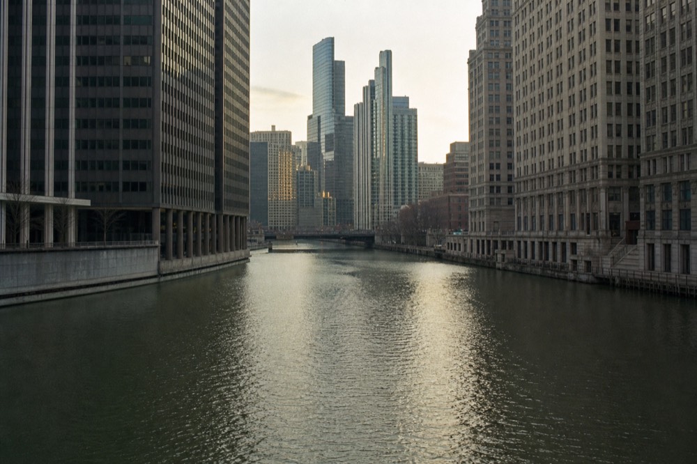Architecture cruise boat moving down the Chicago River between glass towers, no text, no logos, no people.