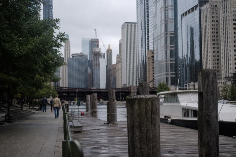 The Chicago Riverwalk promenade under soft morning light, a wooden dock in the foreground with the downtown skyline behind