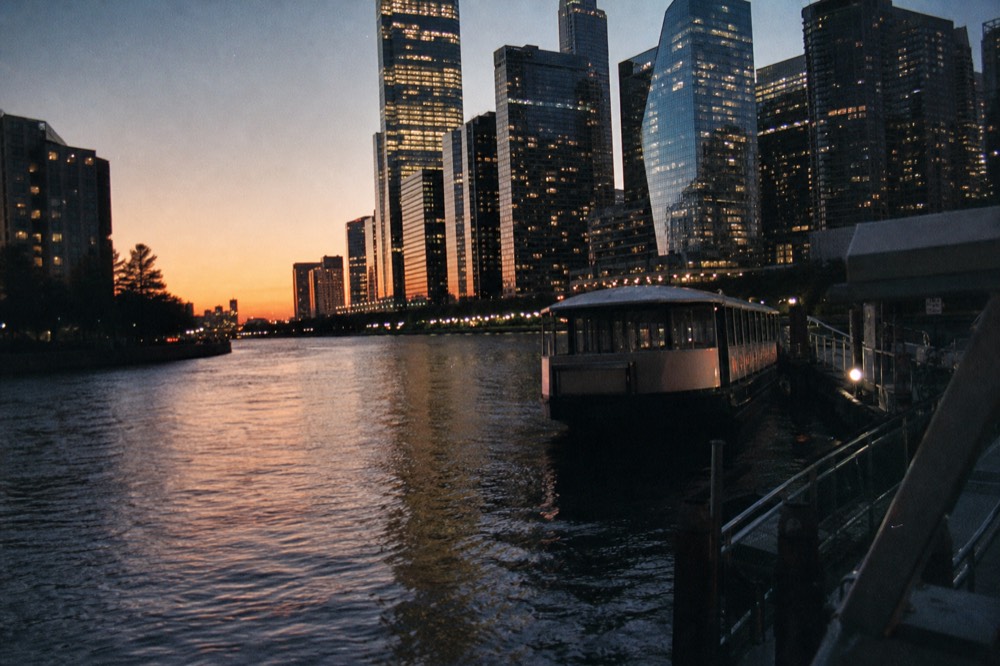 Downtown Chicago towers reflecting evening light over the river with a tour boat at the dock, no text, no logos, no people.