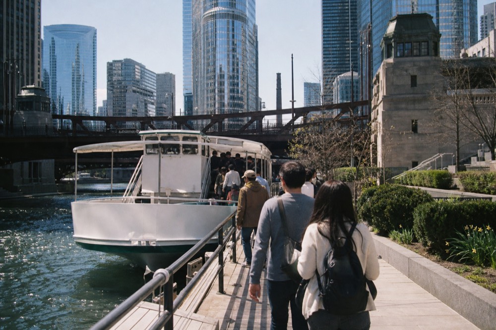 A Chicago River cruise boat tied up along the Riverwalk downtown with bridge towers behind, no text, no logos, no people