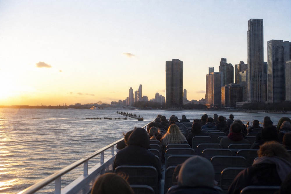Passengers seated on an open upper deck of a Chicago river tour boat facing the skyline, no text, no logos, no people.