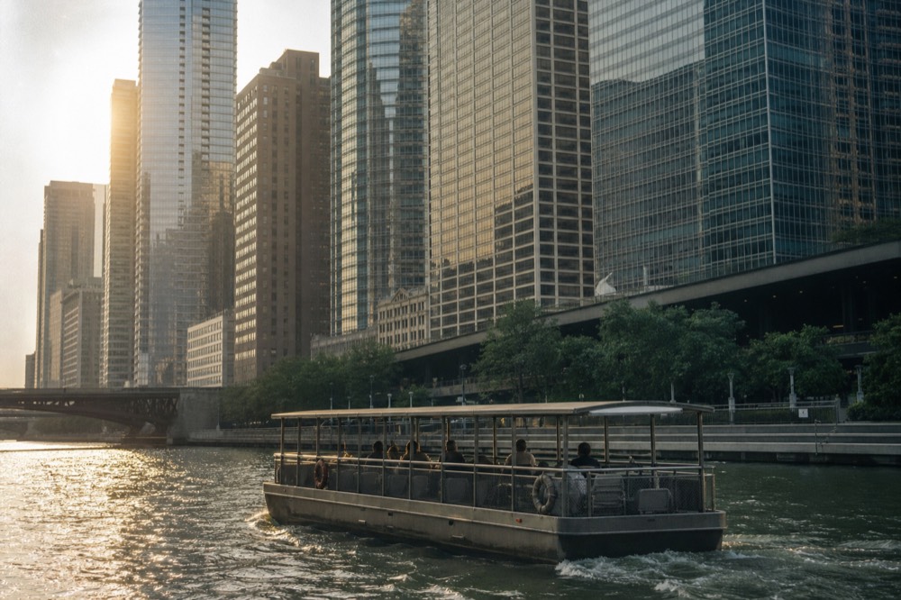 Architecture tour boat passing under a bascule bridge on the Chicago River at golden hour, no text, no logos, no people